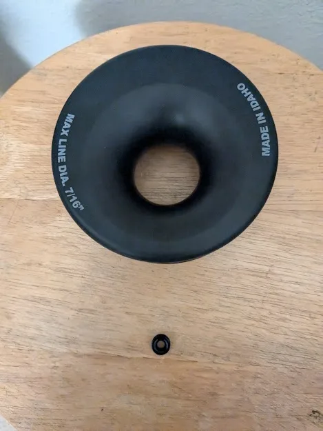 A black rubber donut-shaped object with white text reading 'MADE IN IDAHO' and 'MAX LINE DIA. 7 1/8"' sits on a wooden…