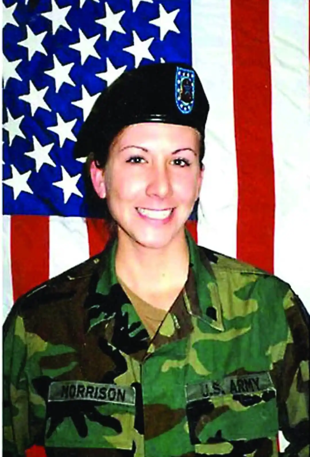 A smiling woman in a U.S. Army camouflage uniform with 'MORRISON' and 'U.S. ARMY' patches on her chest, wearing a black…