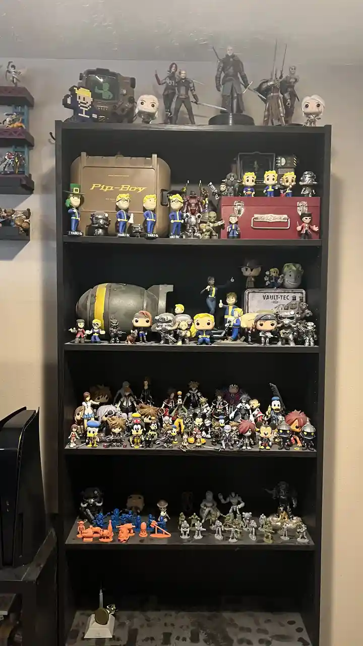 A black shelving unit is filled with numerous pop! vinyl figures and other collectibles from franchises like Fallout…