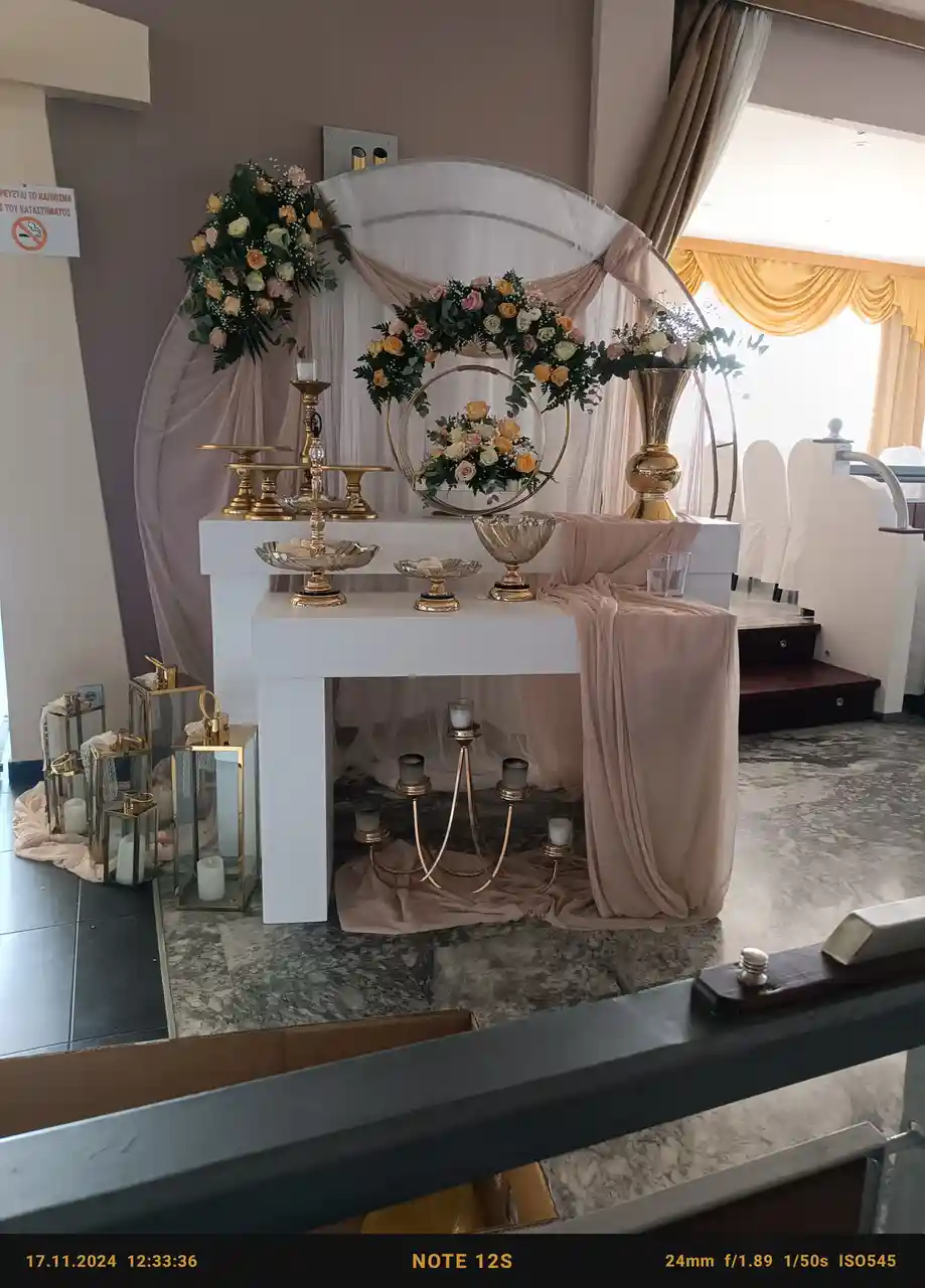 A lavishly decorated wedding altar with gold candlesticks, floral arrangements, and draped fabric, viewed from above with a…