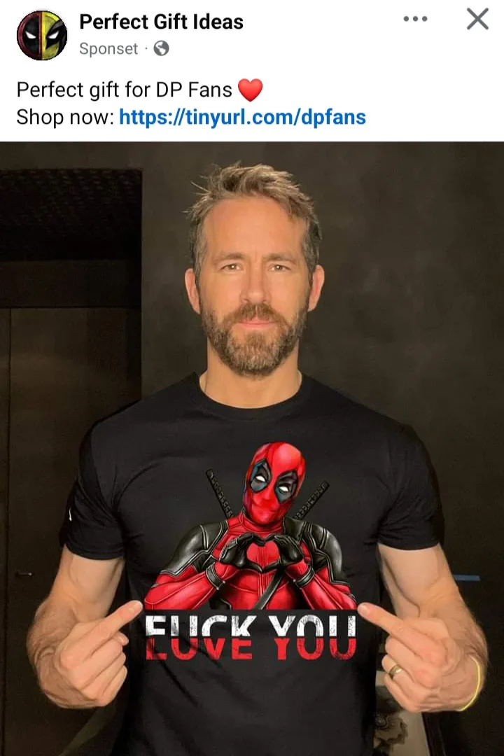 A man with a beard and short hair is wearing a black t-shirt featuring the character Deadpool making a heart shape with his…