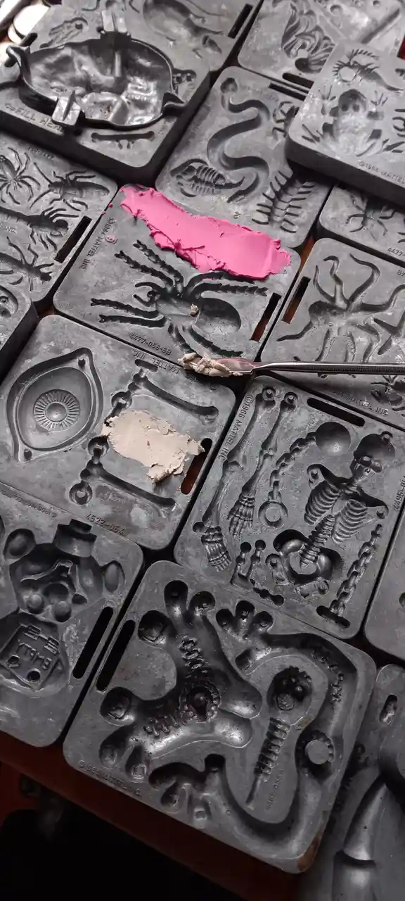 A collection of vintage Mattel Halloween candy molds featuring spiders, skeletons, and other spooky designs, with a pink…