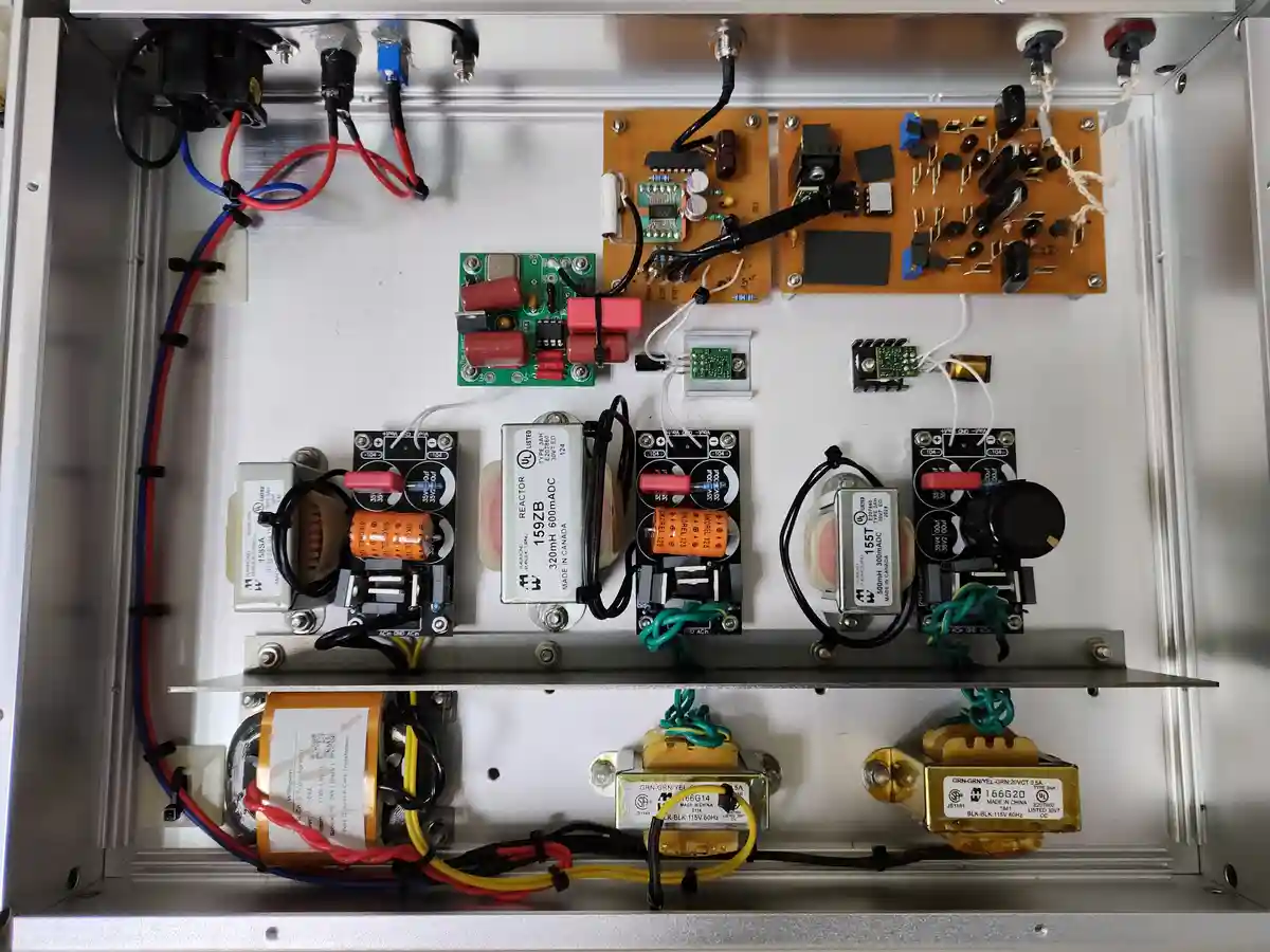 An overhead view of an open electronic device's interior, revealing a complex assembly of circuit boards, capacitors…