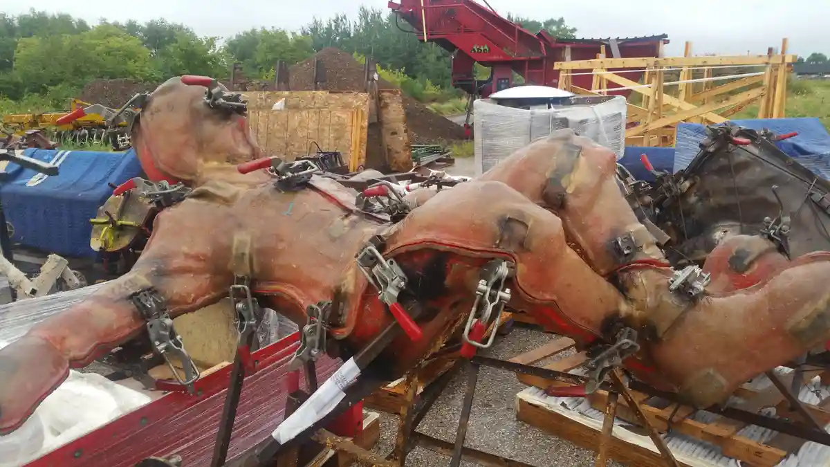 The image shows several large, reddish-brown, sculpted horse-like figures lying on wooden pallets outdoors, secured with…