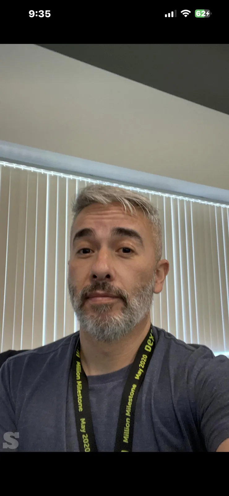 A selfie of a middle-aged man with gray hair and beard wearing a lanyard that reads 'Million Milestone May 2020 Dex'. He has…