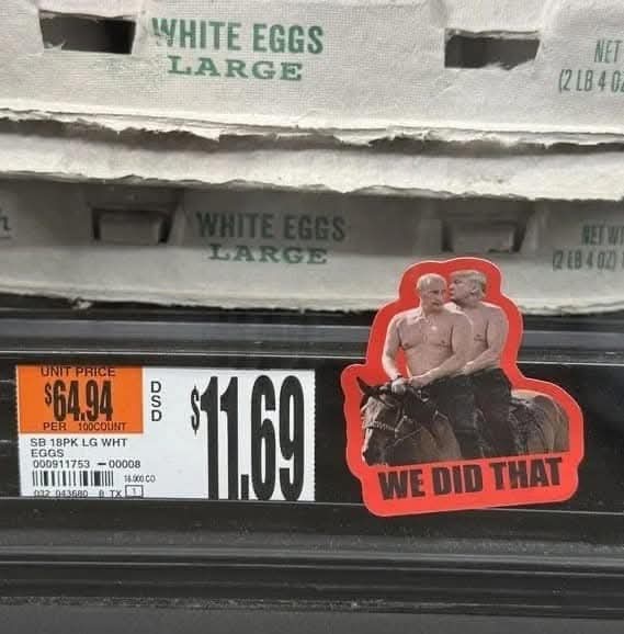 A close-up of a grocery store egg carton priced at $11.69, with a red sticker featuring two shirtless men riding a horse and…