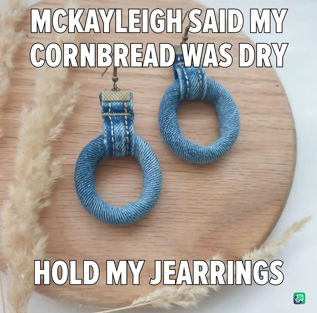 A pair of blue denim earrings shaped like rings sits on a wooden board, flanked by dried pampas grass. The text overlaid in…