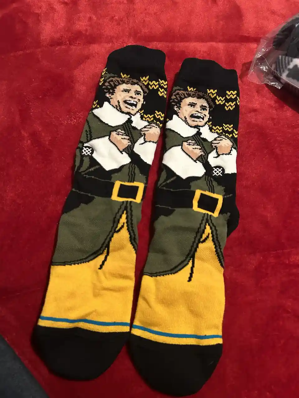 A pair of socks featuring a pixelated image of a man in a green and yellow outfit with a white collar, screaming with his…
