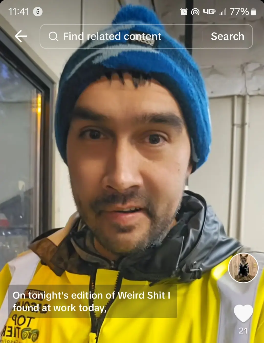 A man wearing a blue beanie and a yellow high-visibility jacket looks directly at the camera with a surprised expression…