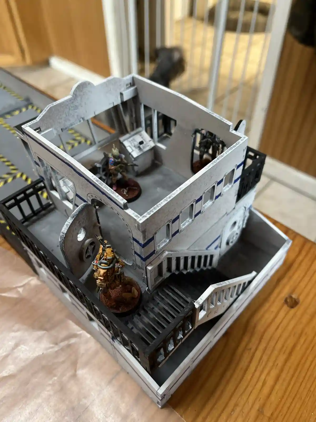 A detailed miniature spaceship model, painted white with blue stripes and featuring stairs, railings, and windows, is…