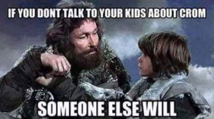A man with a beard and rugged clothing points sternly at a young child in similar attire. The image has white text overlaid…