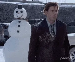 A man in a suit stands beside a snowman, then the snowman suddenly transforms into a person in an orange jumpsuit who…