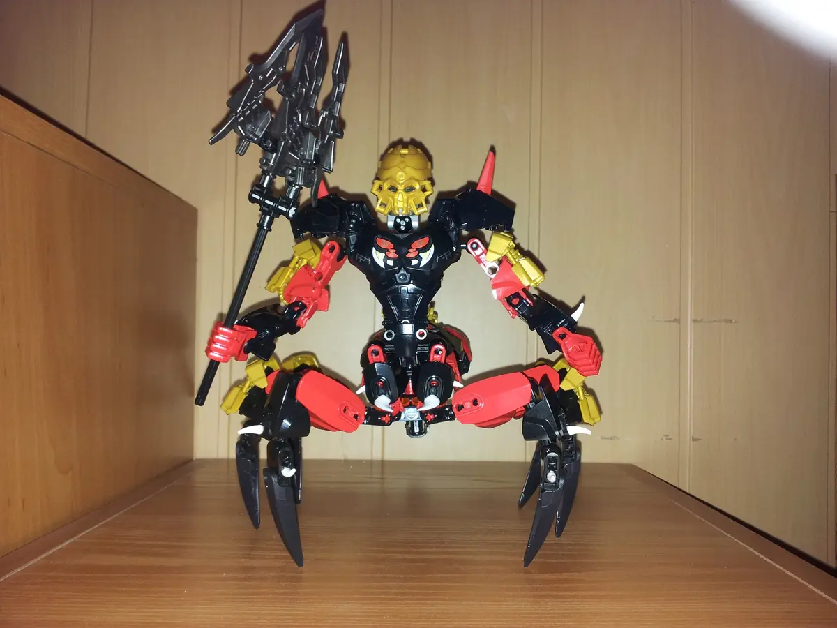 A custom-built Bionicle-style action figure with a black, red, and yellow color scheme stands on a wooden shelf, holding a…