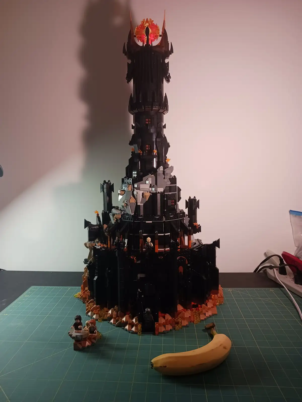 A large, intricate LEGO model of the Dark Tower from The Lord of the Rings, featuring a glowing Eye of Sauron at the top…