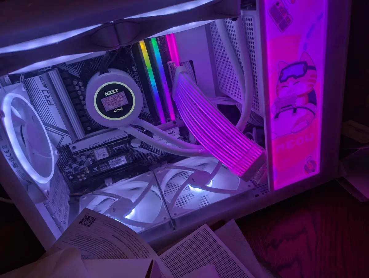 A close-up of a custom-built PC's interior, illuminated with purple and white LED lighting, showing a liquid cooling pump…