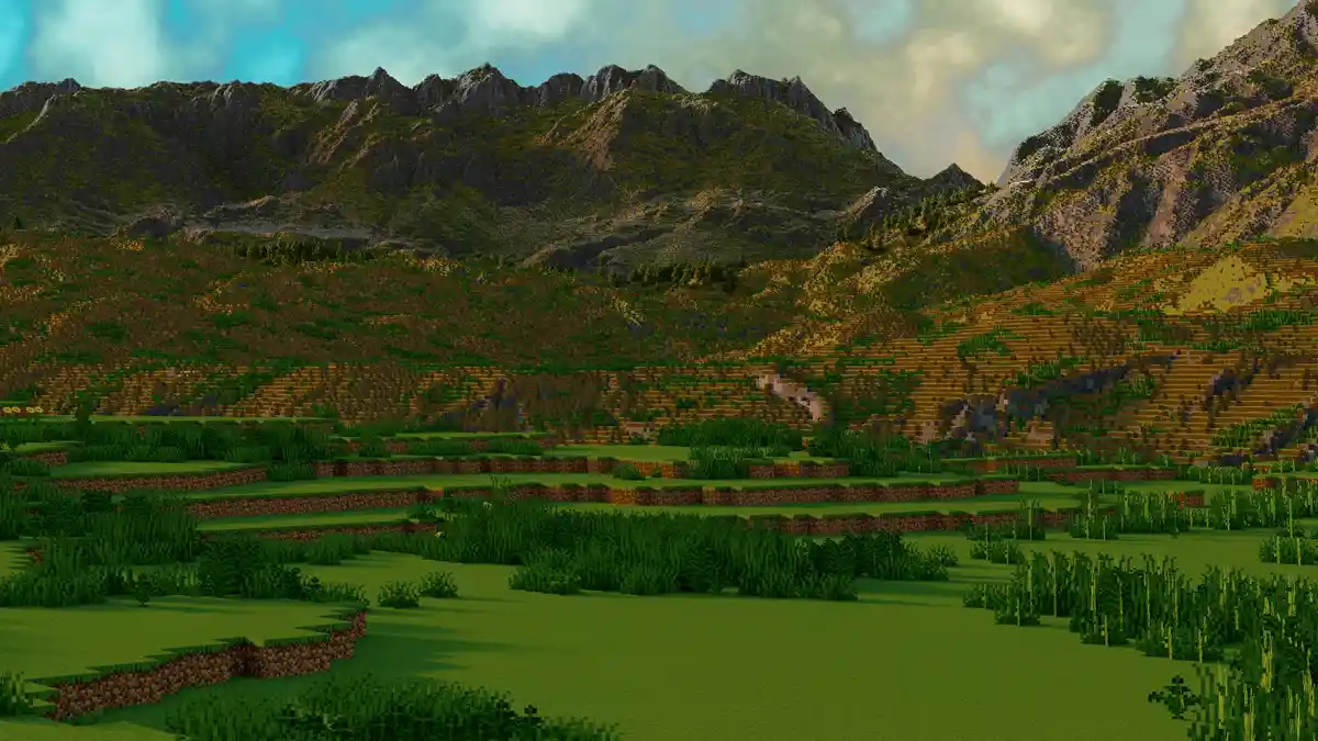 A screenshot of a Minecraft landscape featuring rolling hills, terraced farmland, and distant mountains under a cloudy sky…