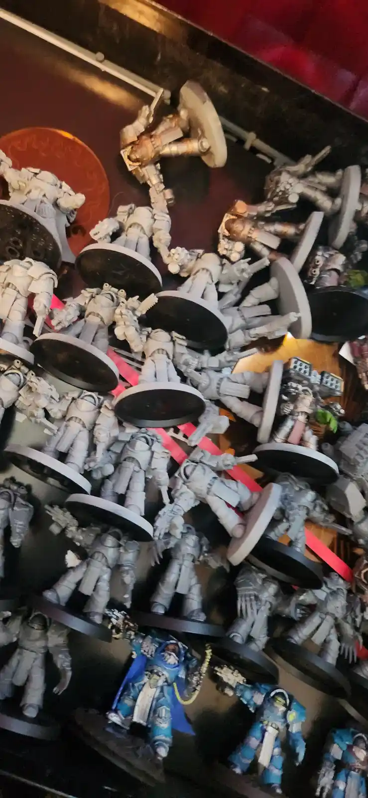 A large pile of unpainted, grey miniature figurines with round bases, mostly resembling futuristic soldiers or space…