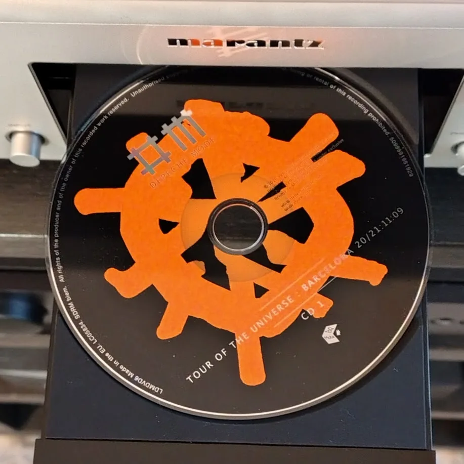 A close-up photo of a Depeche Mode CD titled 'Tour of the Universe' inserted into a Marantz CD player. The CD's original…
