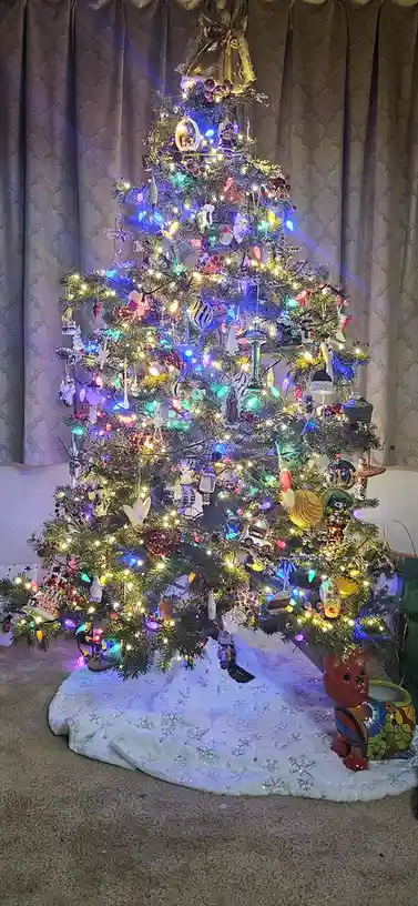 a full, brightly lit christmas tree is densely covered with colorful lights and an overwhelming variety of ornaments…
