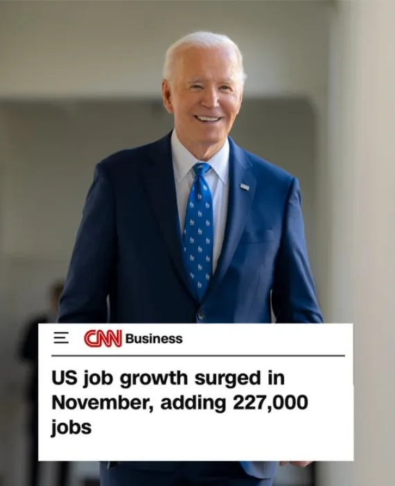 A smiling man in a blue suit and patterned tie stands behind a CNN Business news graphic that reads 'US job growth surged in…
