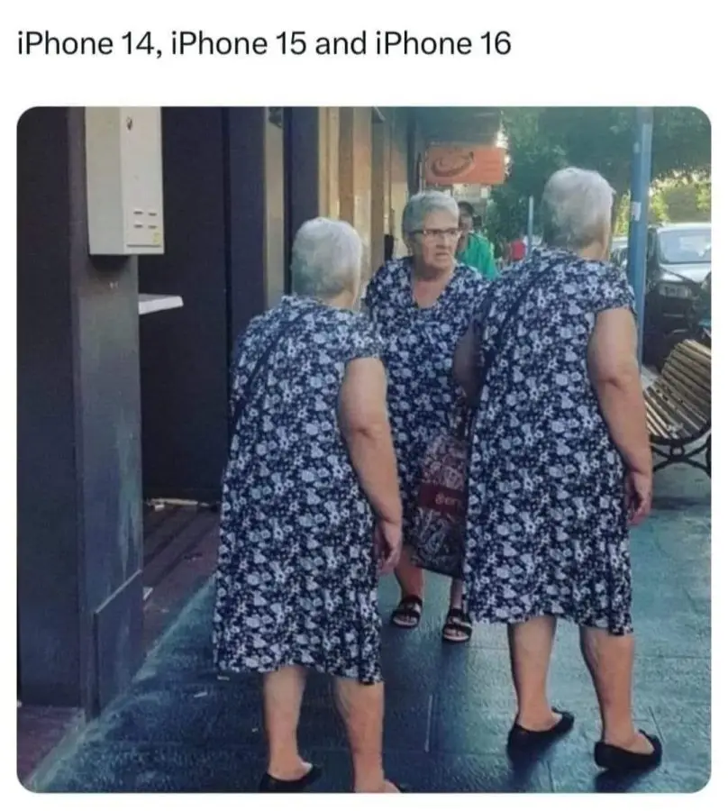 Three elderly women in matching blue and white floral dresses stand on a sidewalk. The woman in the middle faces forward…