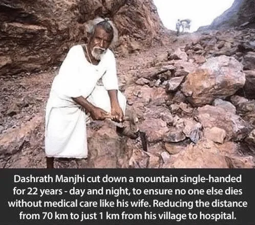 An elderly man with a white beard and traditional white clothing is shown kneeling on a rocky, mountainous terrain, actively…