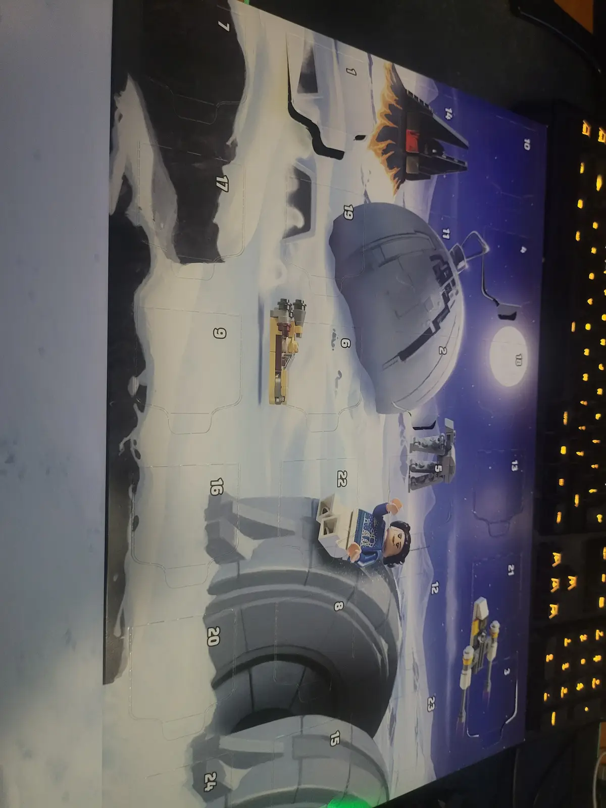 A close-up photo of a partially opened LEGO Star Wars Advent Calendar, showing numbered compartments with some LEGO models…