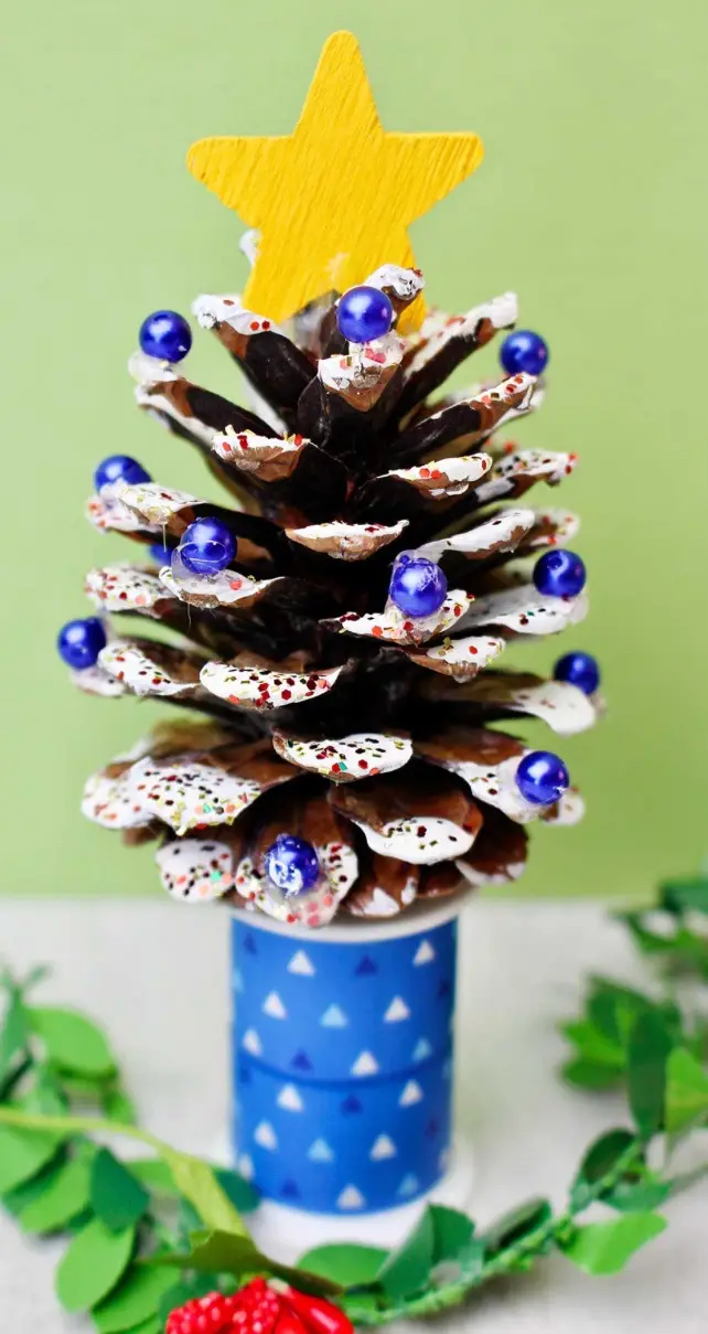 a pinecone has been creatively decorated to resemble a christmas tree, with its scales painted white and adorned with blue…