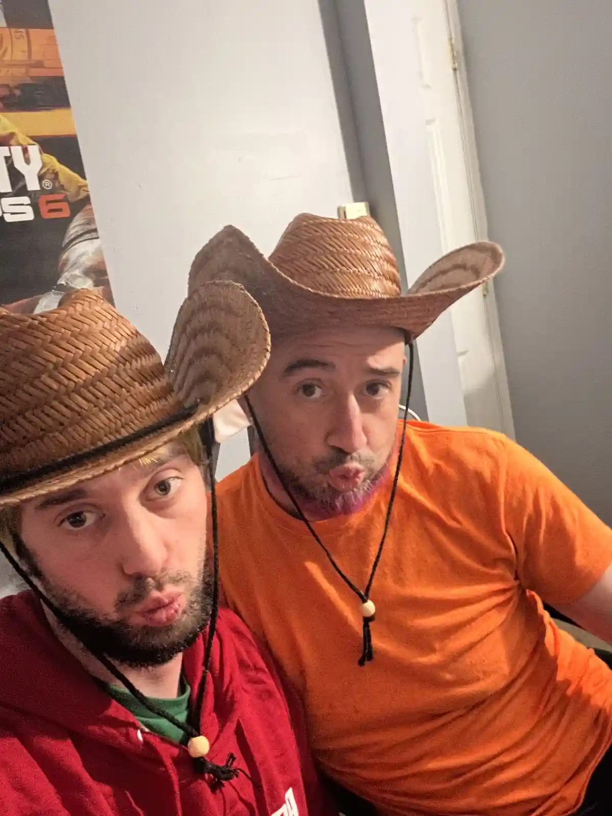 Two men wearing straw cowboy hats pose for a selfie with exaggerated puckered lips and wide eyes. The man on the left wears…