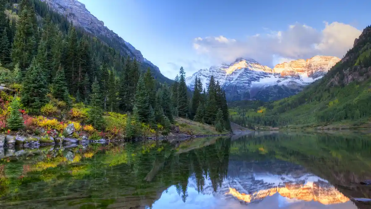 In the Colorado Rockies, the Maroon Bells, two iconic 14ers, stand majestically before Maroon Lake. The twins' rust-hued…