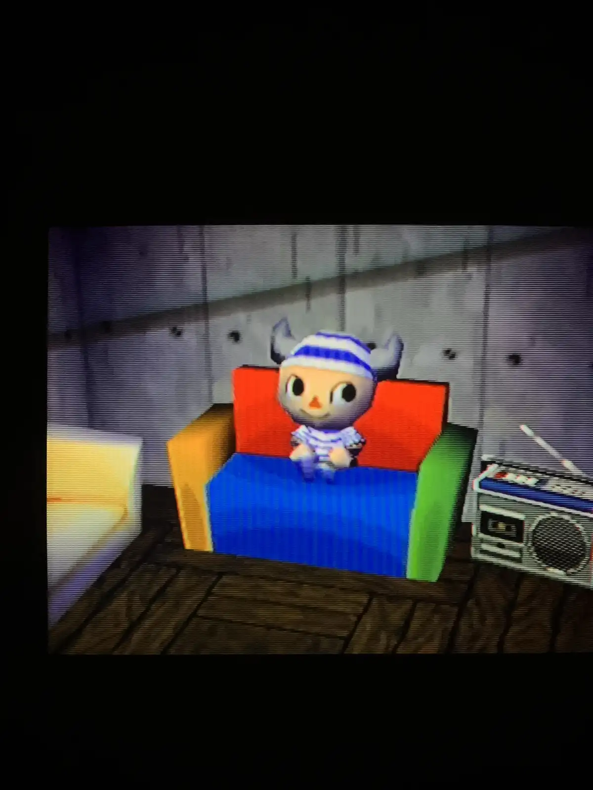 A screenshot from Animal Crossing shows a gray, horned animal character wearing a blue-and-white striped hat and shirt…