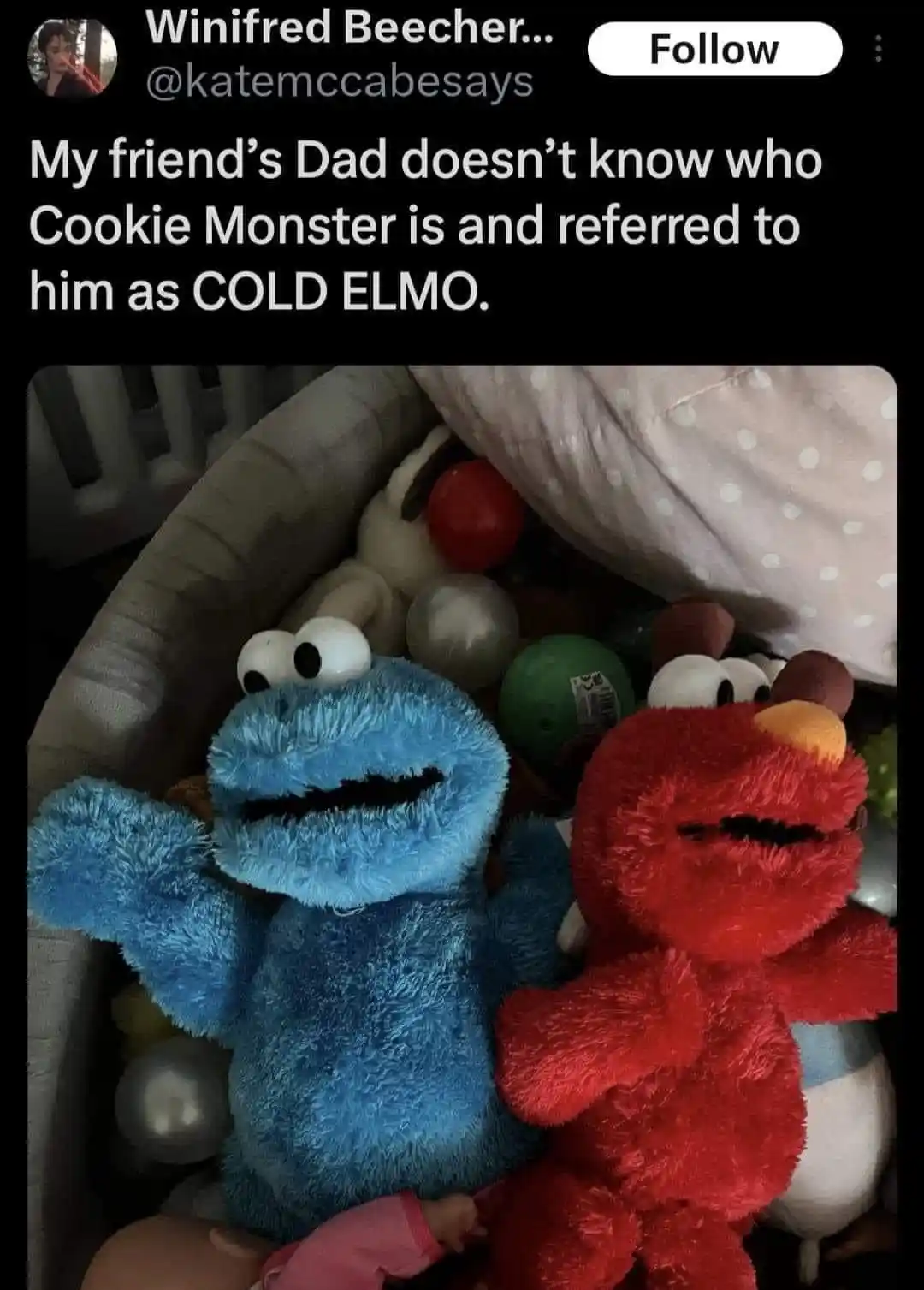 A photo shows two plush toys, a blue Cookie Monster and a red Elmo, sitting side-by-side in a pile of other toys. The…