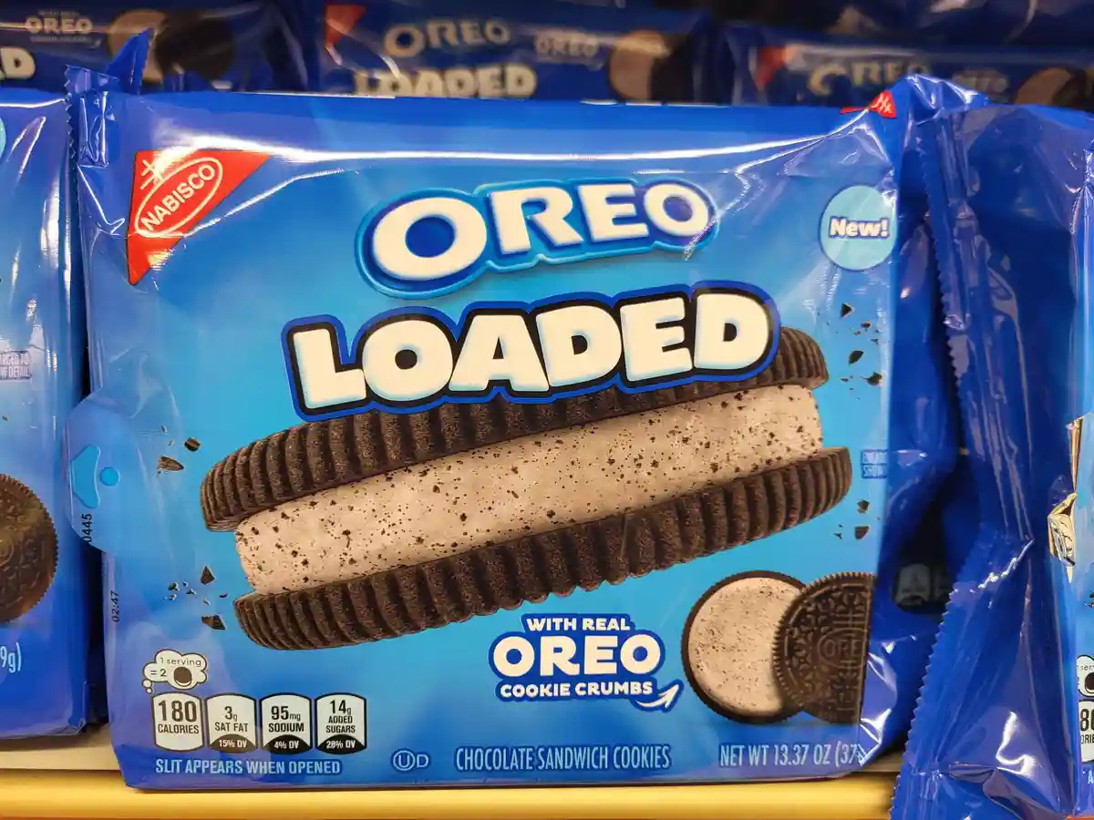 A close-up of a blue Oreo Loaded cookie package on a store shelf, featuring a large image of a cookie with cookie crumbs in…