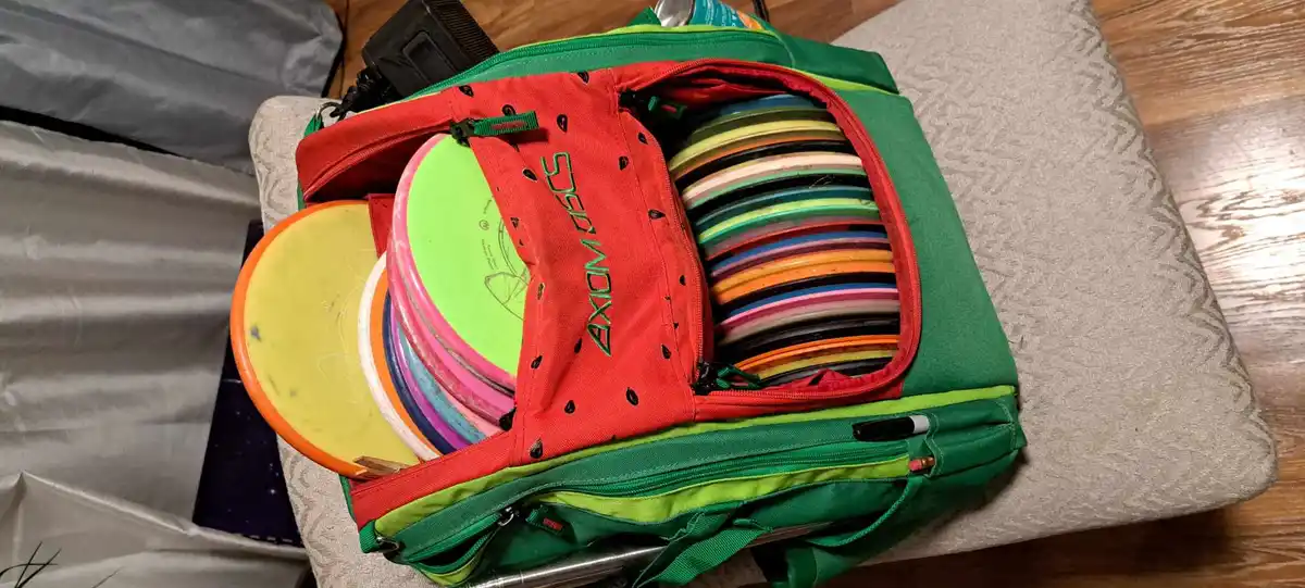 A green and red bag designed to look like a watermelon, with black seeds printed on the red section, is open and overflowing…