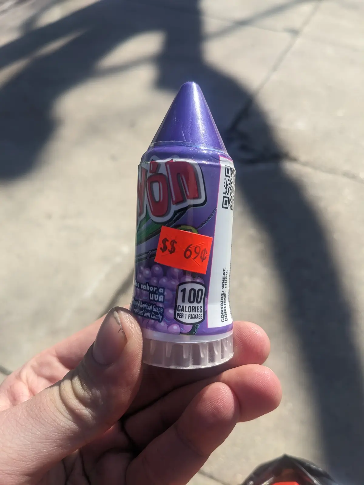 A hand holds a small, purple, cone-shaped package of grape-flavored soft candy labeled 'YON' with a bright orange sticker…