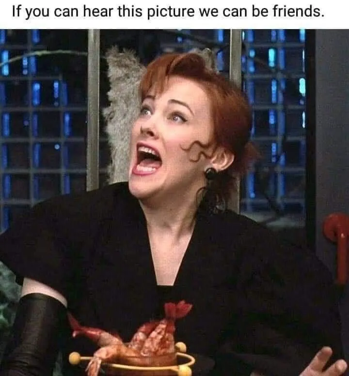 A woman with red hair and black clothing is shown with her mouth wide open in a scream, holding a dish with a cooked…