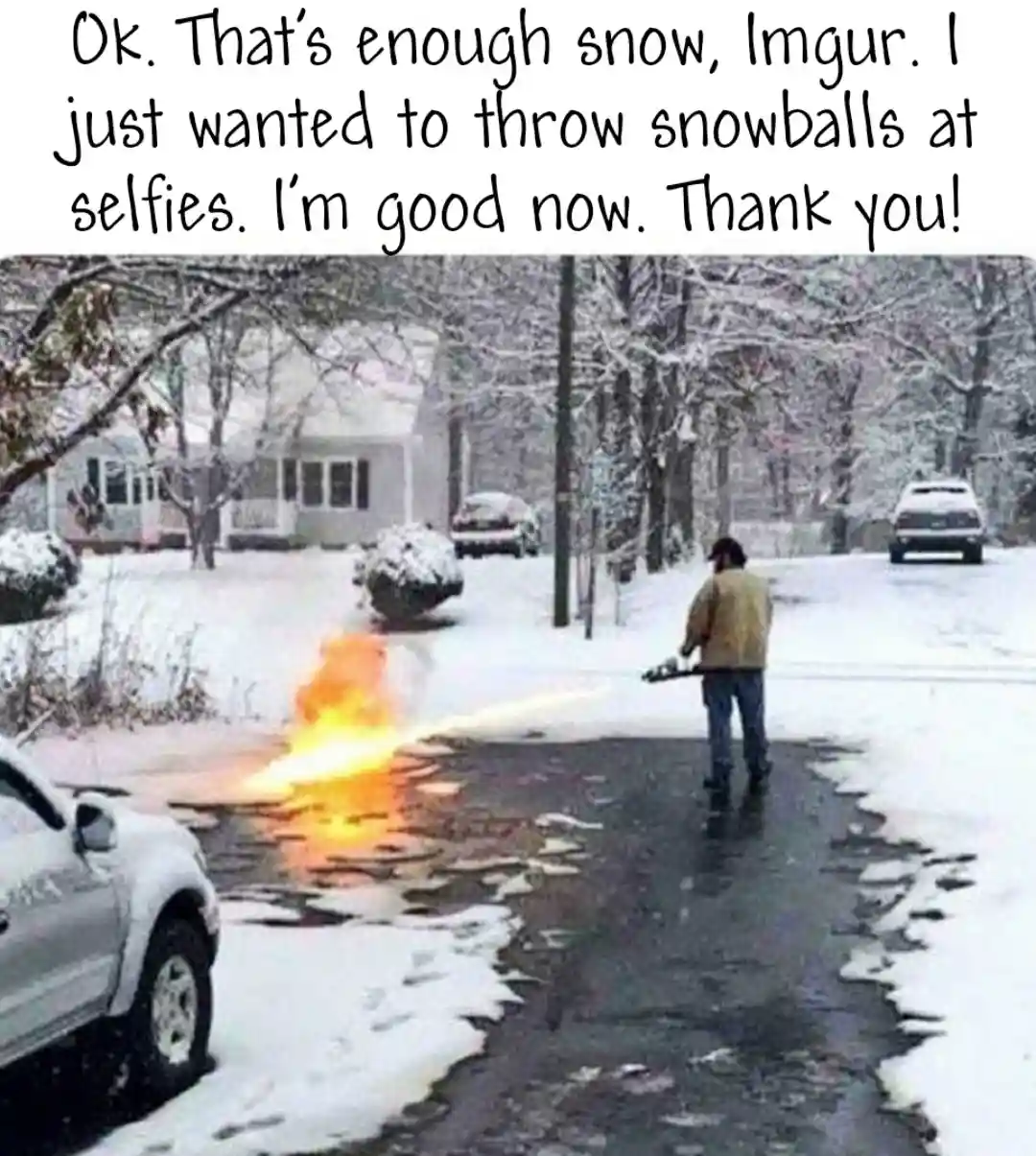 A person in a yellow jacket stands on a snowy street holding a chainsaw, with a bright orange flame erupting from the…