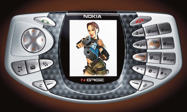 A silver Nokia N-Gage gaming phone with a screen displaying a video game character holding a gun. The phone has a…