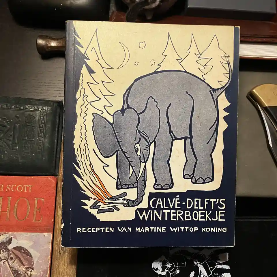 A vintage Dutch cookbook titled 'Calvé-Delft's Winterboekje' with a stylized illustration of an elephant using its trunk to…