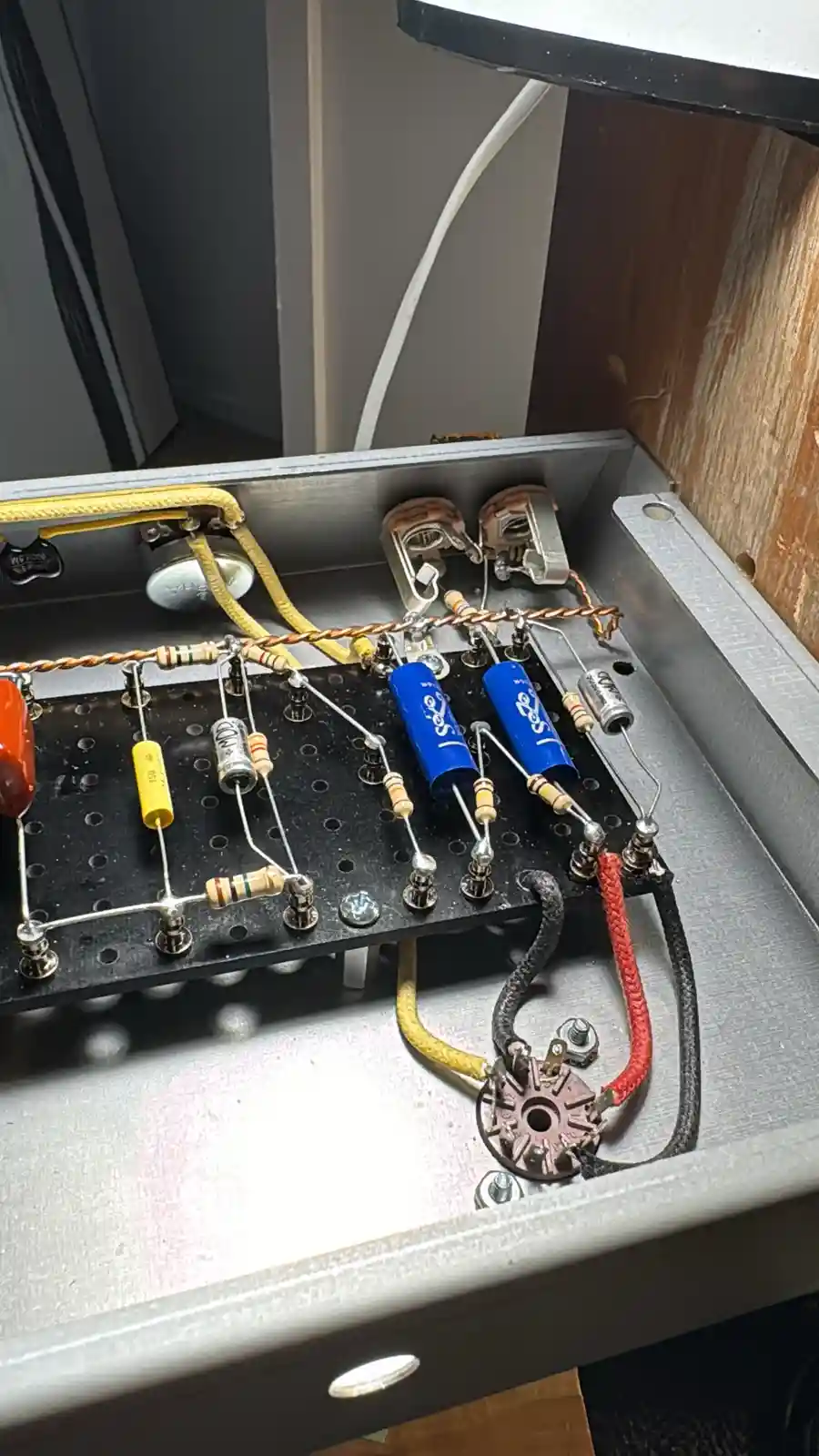 A close-up photo of the internal circuitry of an amplifier, showing various electronic components like capacitors…