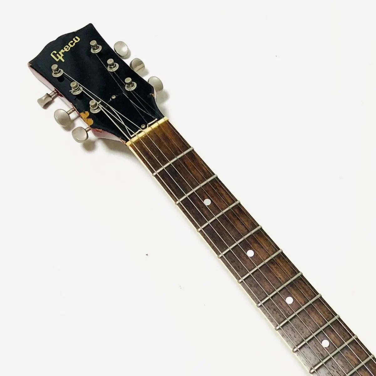 A close-up photo of a Grecu brand guitar headstock and fretboard against a plain white background. The guitar has six tuning…