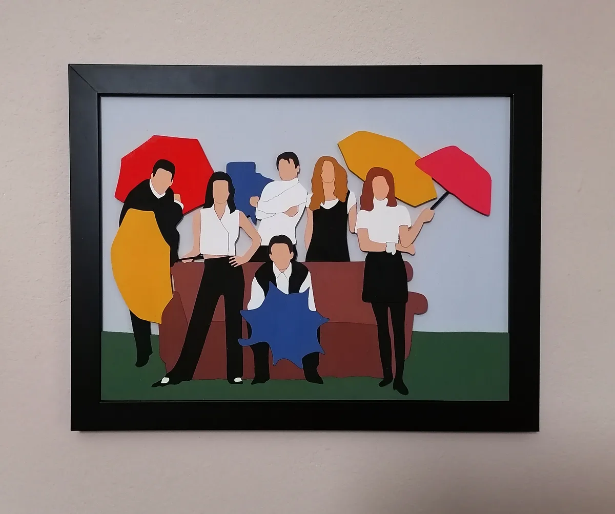 A framed, stylized paper-cut art piece depicts six faceless figures in 1990s-style clothing, some holding umbrellas…