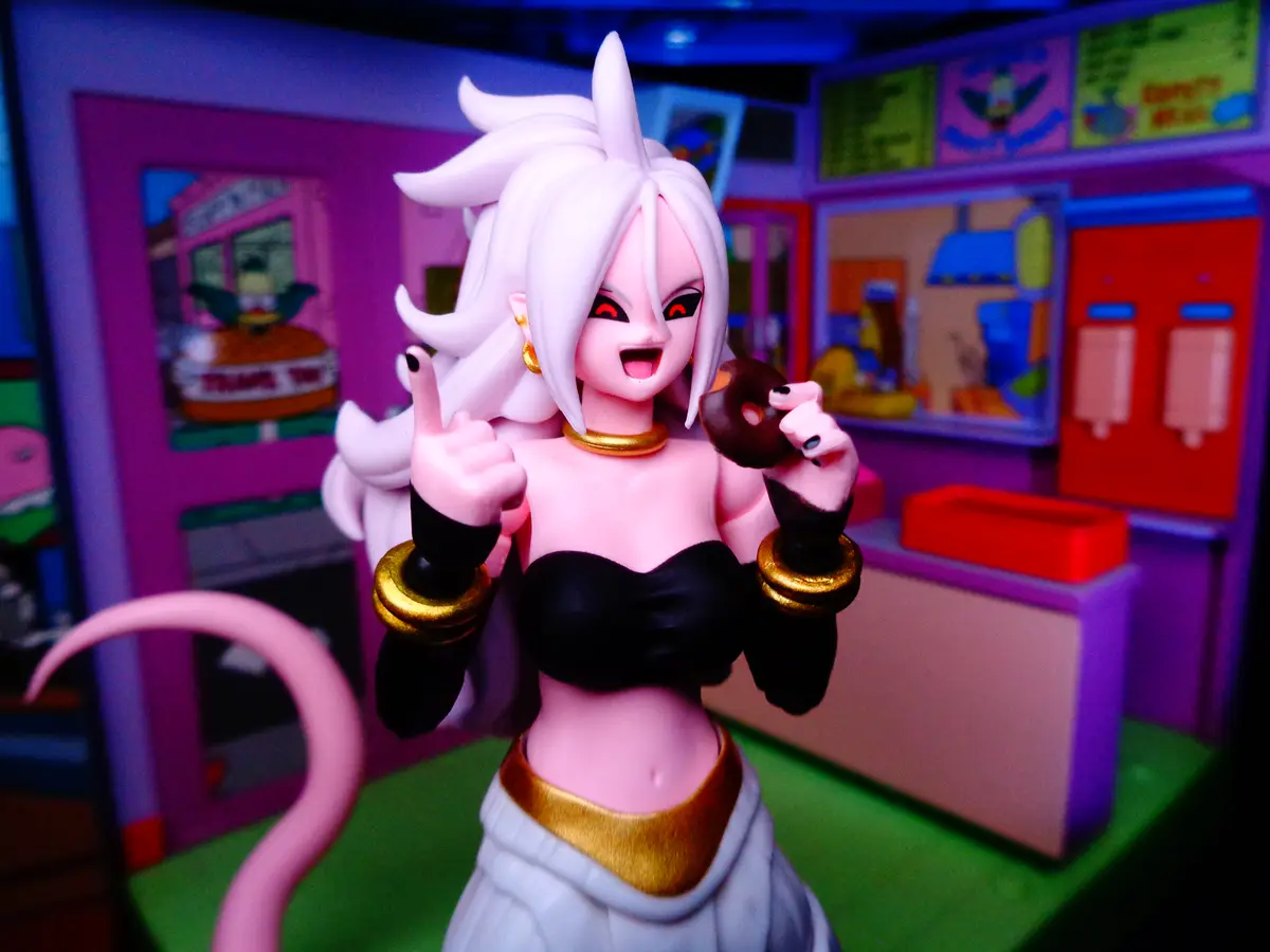 A figurine of the anime character Android 17, with white hair and red eyes, is shown in a brightly colored, cartoonish diner…