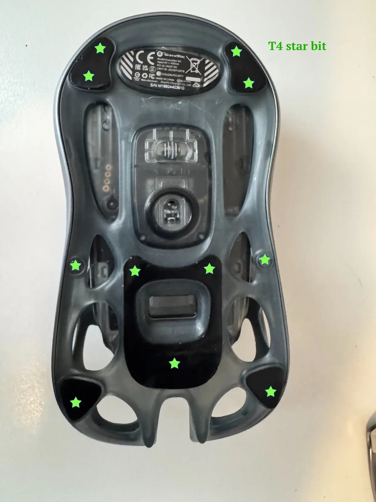 The underside of a black electronic device, likely a scooter or hoverboard, is shown with eight glowing green stars…