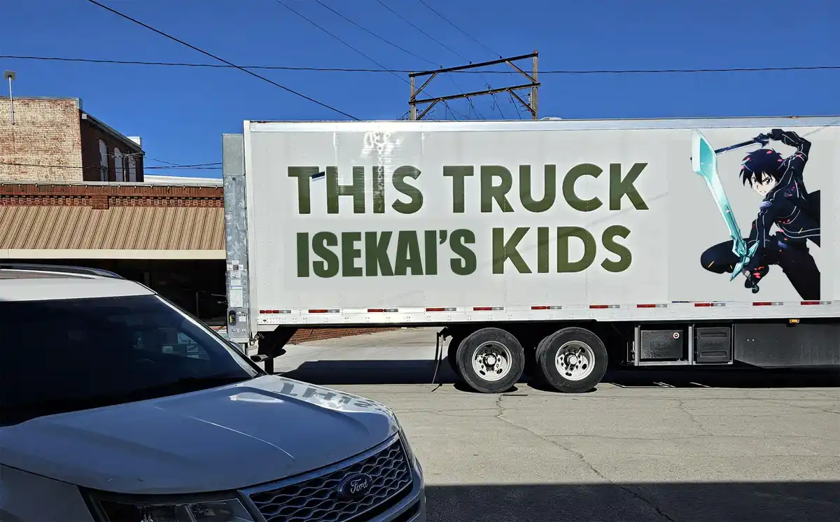 A large white semi-trailer truck parked outdoors under a clear blue sky, with bold green text reading 'THIS TRUCK ISEKAI'S…
