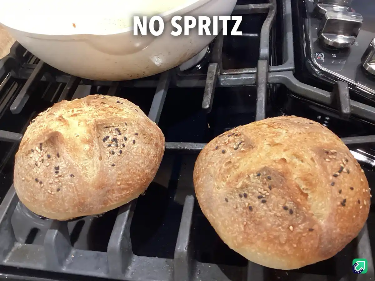 Two round, golden-brown seeded bread rolls sit on a black gas stove grate, with a white pot visible in the background. The…