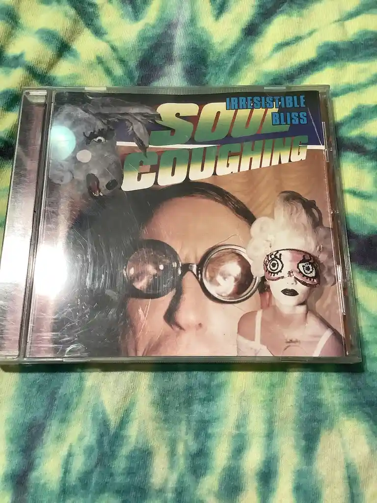 A CD case for the band Soul Coughing, featuring the album title 'Irresistible Bliss' in stylized text. The cover art shows a…