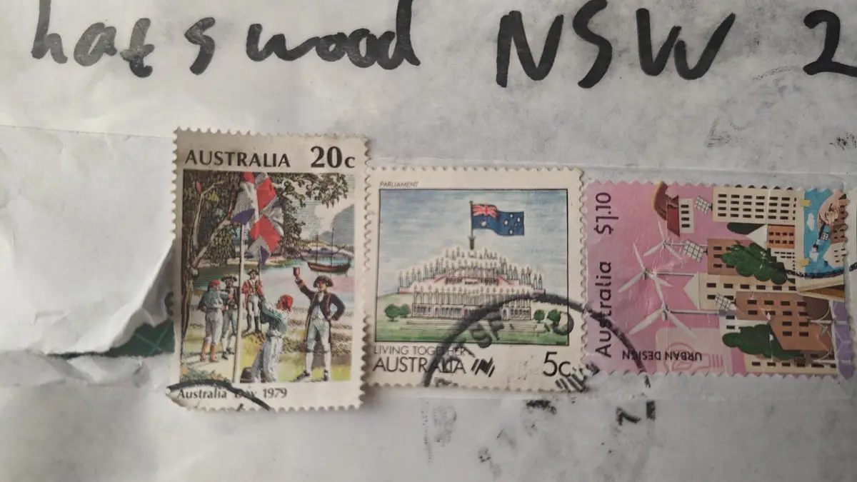 Three Australian postage stamps are affixed to an envelope with handwritten text above reading 'hat's wood NSW 2'. The left…