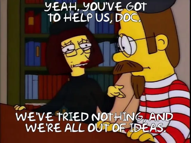 A still from The Simpsons shows a woman with glasses and dark hair sitting at a desk, looking frustrated while speaking to a…