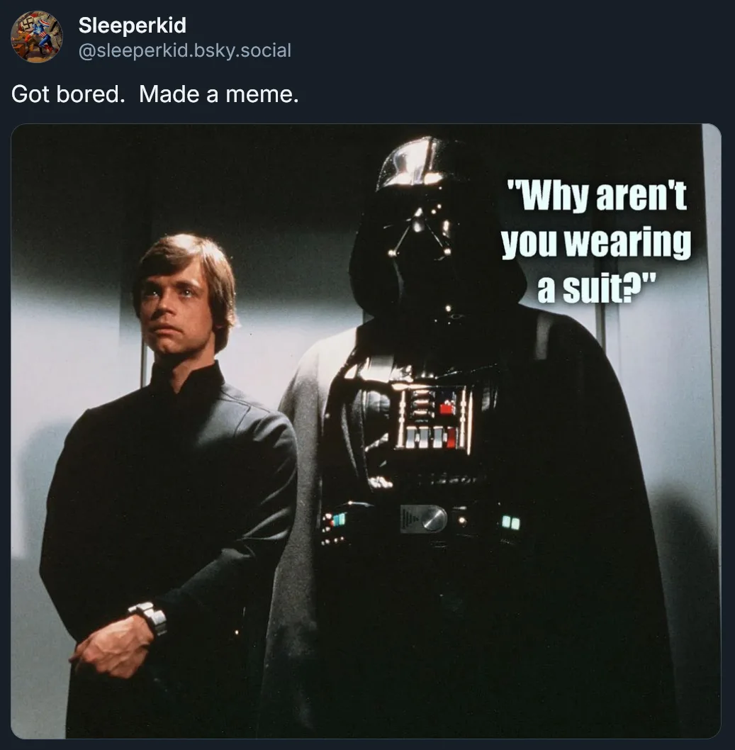 A still image from Star Wars shows Darth Vader standing beside Luke Skywalker, who is wearing a dark, simple tunic. White…
